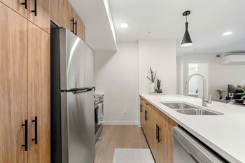 A modern kitchen with a stainless steel refrigerator and wooden cabinets.at Skyway Apartments, Alberta, T3B 5V6